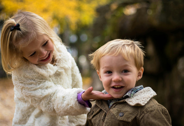 Two children playing outdoors with a blurred natural background